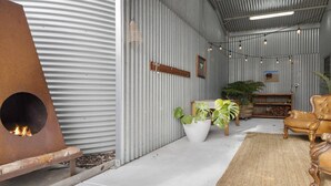 A rustic interior with a fireplace, leather armchairs, potted plants, and string lights. - The Cubby House by Wine Coast Holiday Rentals (WHITES VALLEY)