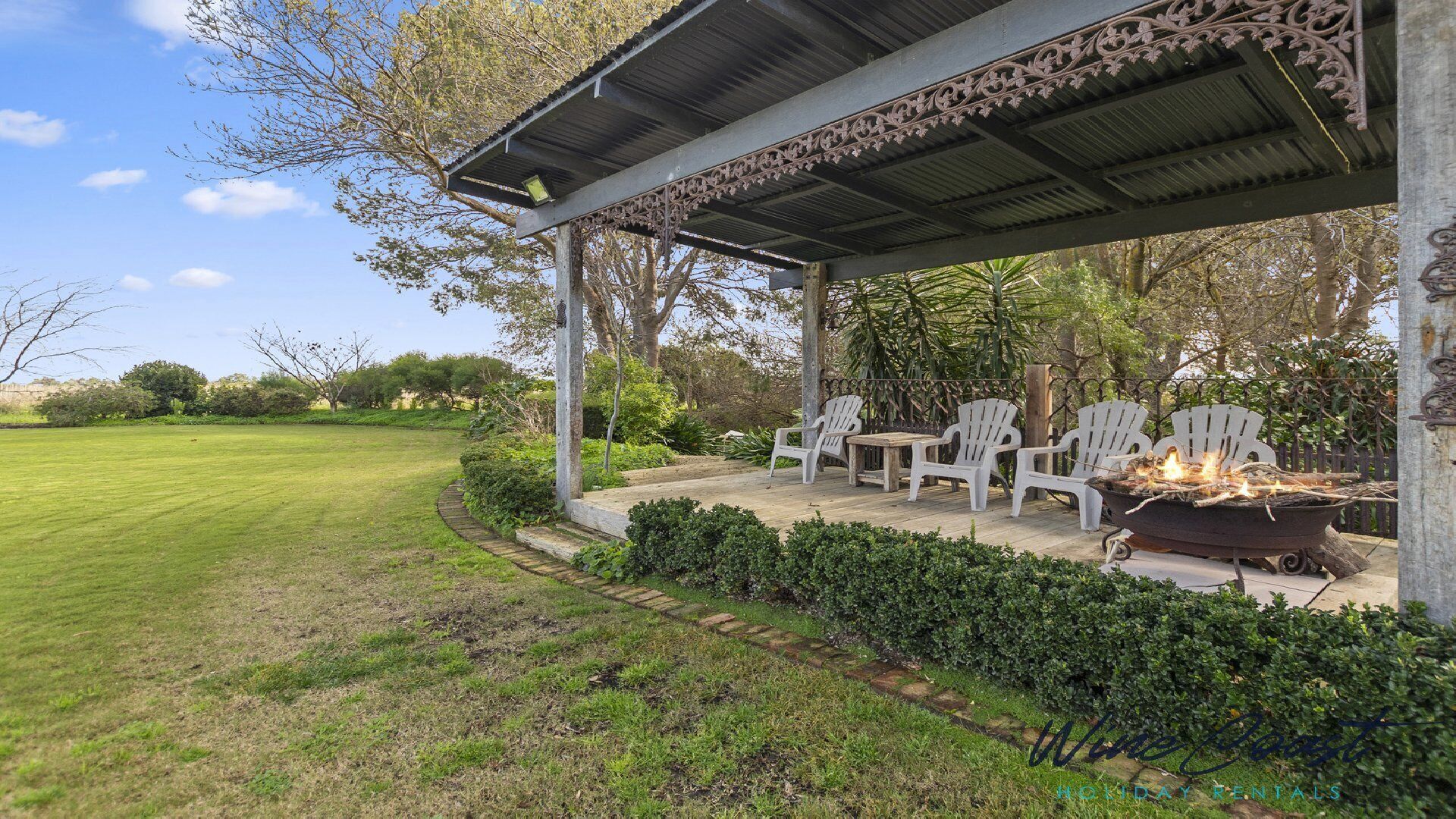 A covered outdoor seating area with chairs and a fire pit.