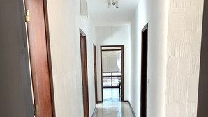 A corridor with tiled flooring, wooden doors, and white walls.