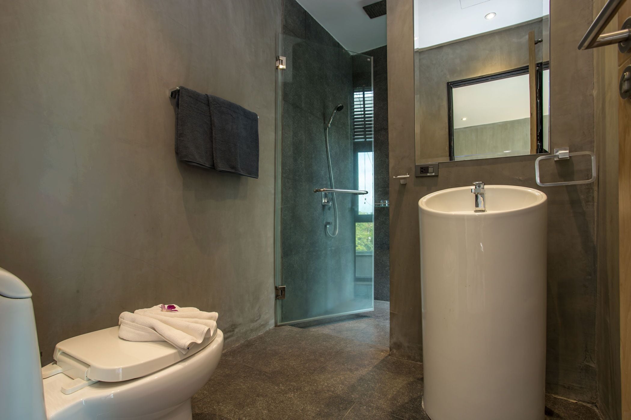 A modern bathroom with a toilet, a sink, and a shower.