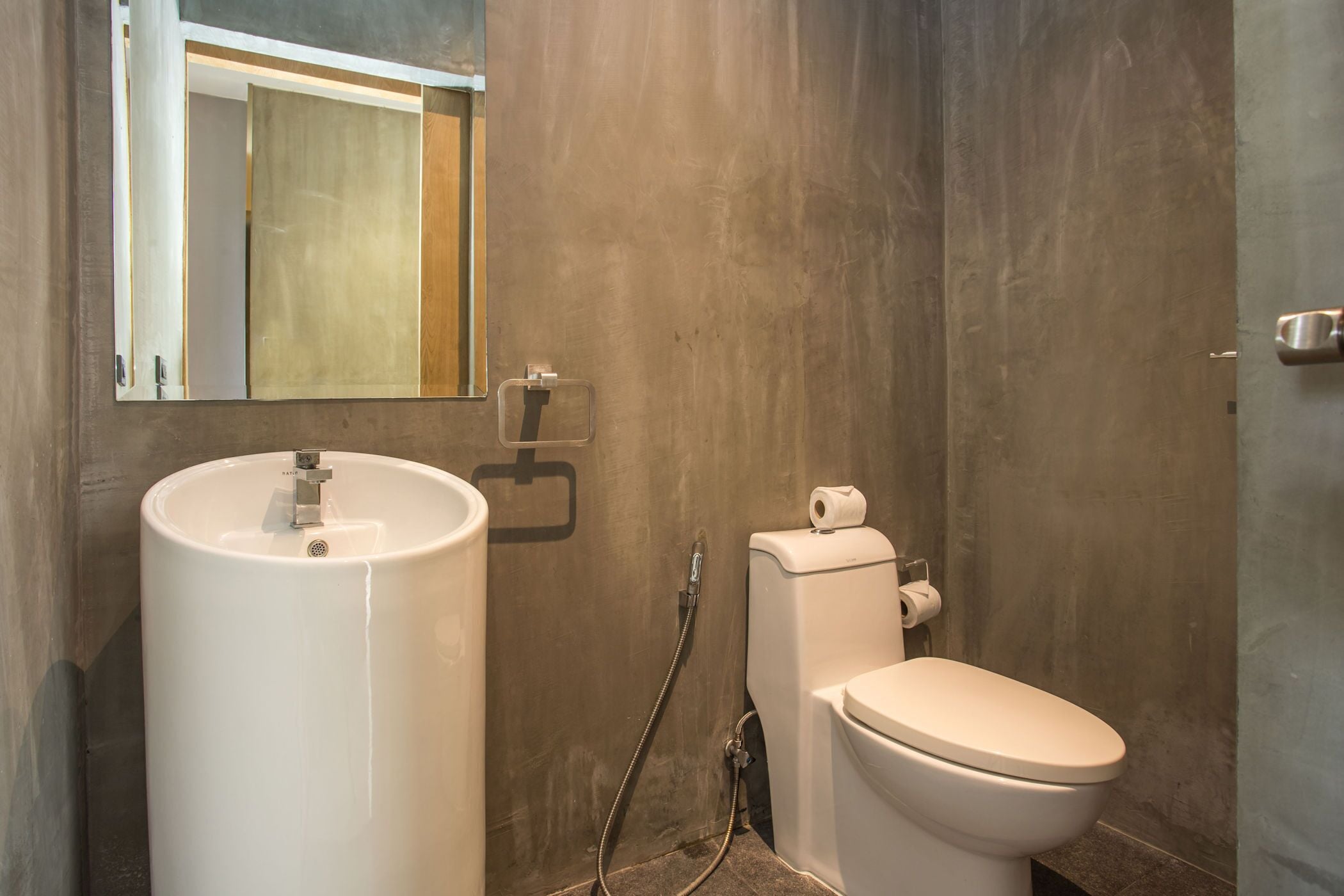 A bathroom with a large white sink, a toilet, and a mirror.