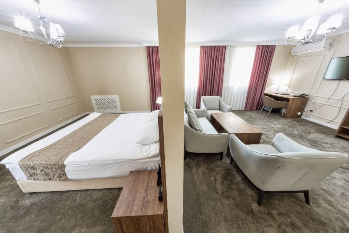 A hotel room with a bed, a desk, a chair, and a TV.