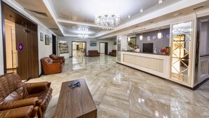 Un'ampia hall con reception, posti a sedere in pelle e un lampadario.