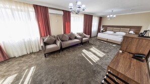 Una camera d'albergo con un letto grande, un divano, una scrivania in legno e un lampadario.