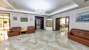 Un'ampia hall con soffitto alto, un lampadario e una reception.