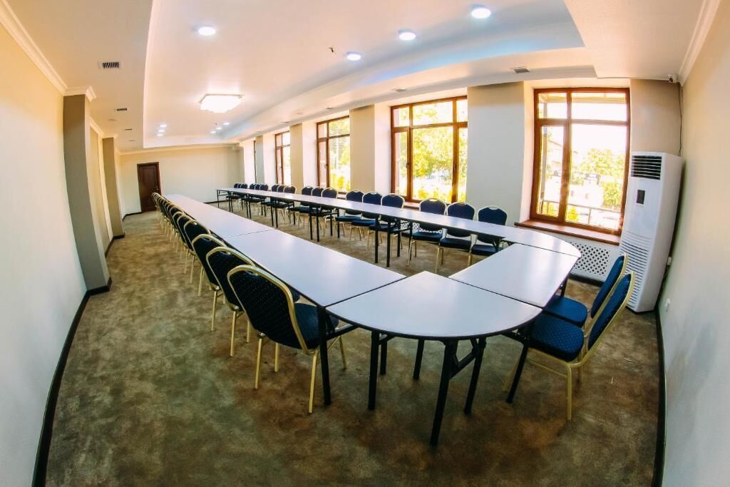 A conference room with a long table and chairs, large windows, and an air conditioning unit.