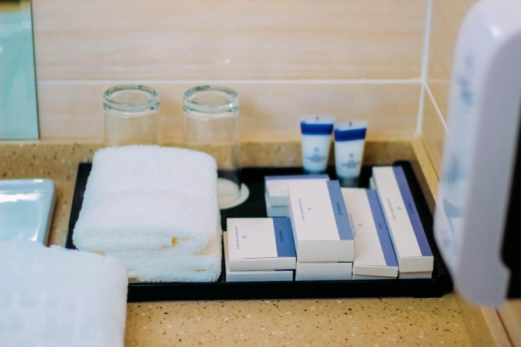 Ein Badezimmer-Waschtisch mit Pflegeprodukten, einem weißen Handtuch und zwei Glasbehältern.