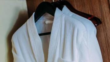 A white bathrobe hanging on a wooden door.