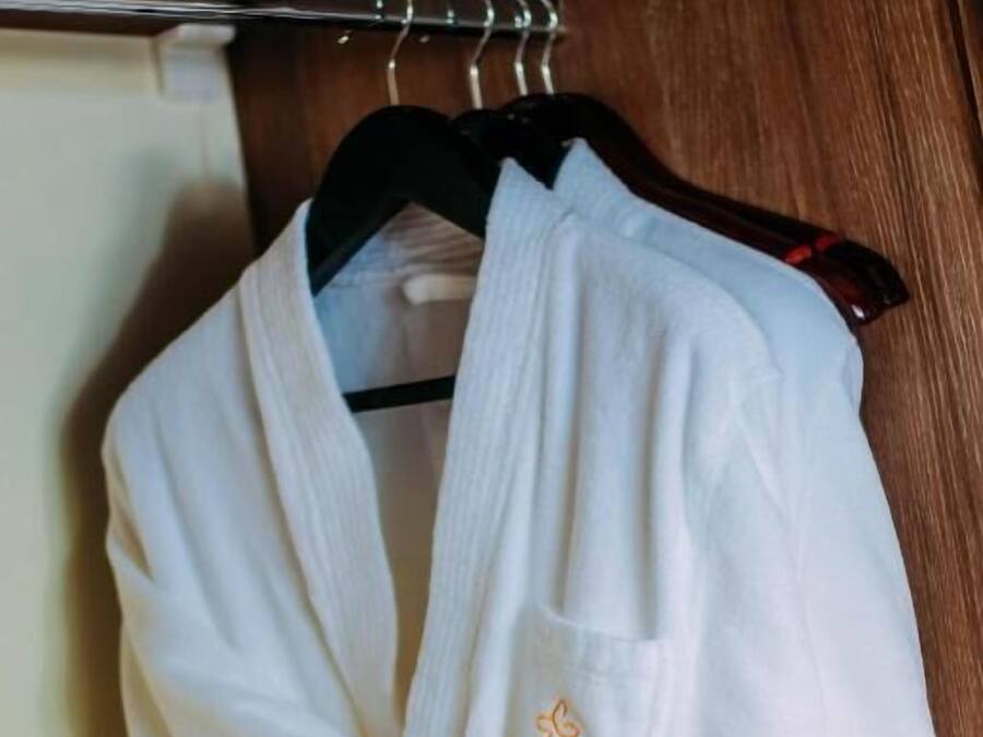 A white bathrobe hanging on a wooden door.