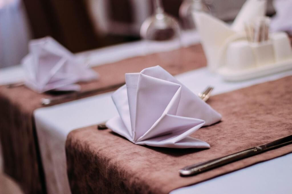 A table with a folded napkin and a pen on a tablecloth.