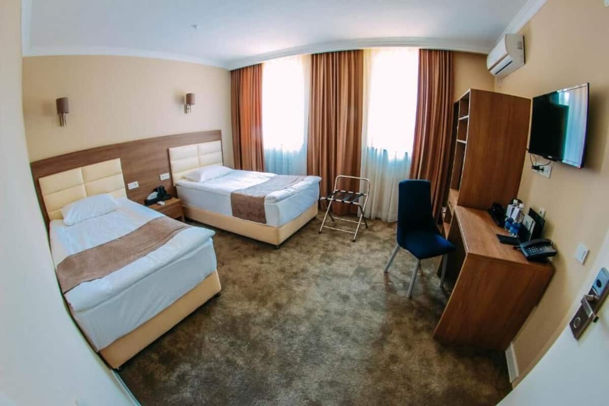 A hotel room with two beds, a desk, a chair, a TV, and a wardrobe.