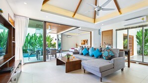 A spacious living area with a grey sofa, wooden coffee table, and a ceiling fan. - Two Storey Villa Kael in KA Villas Rawai (Rawai)