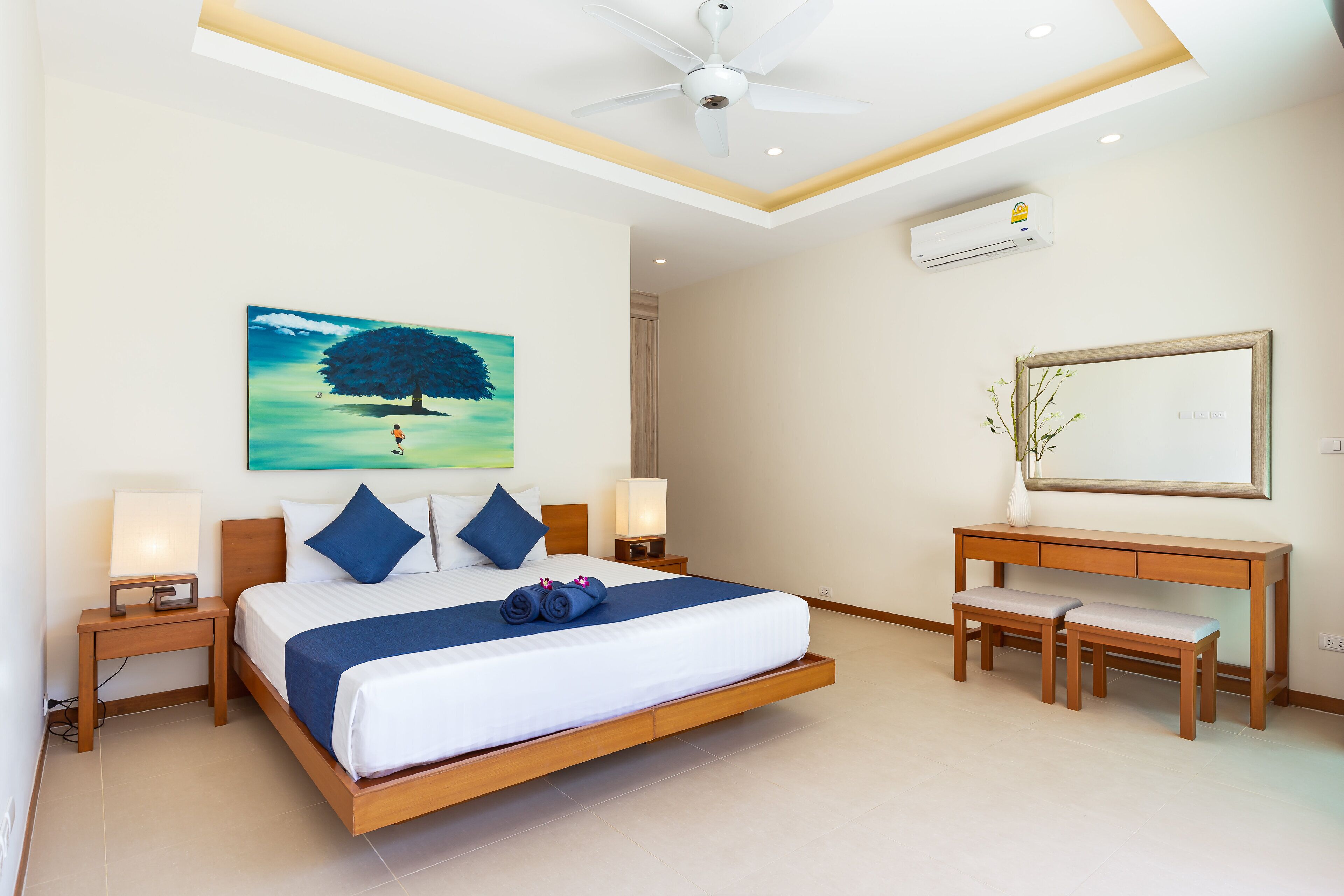 A modern bedroom with a bed, bedside tables, a desk, and a chair.