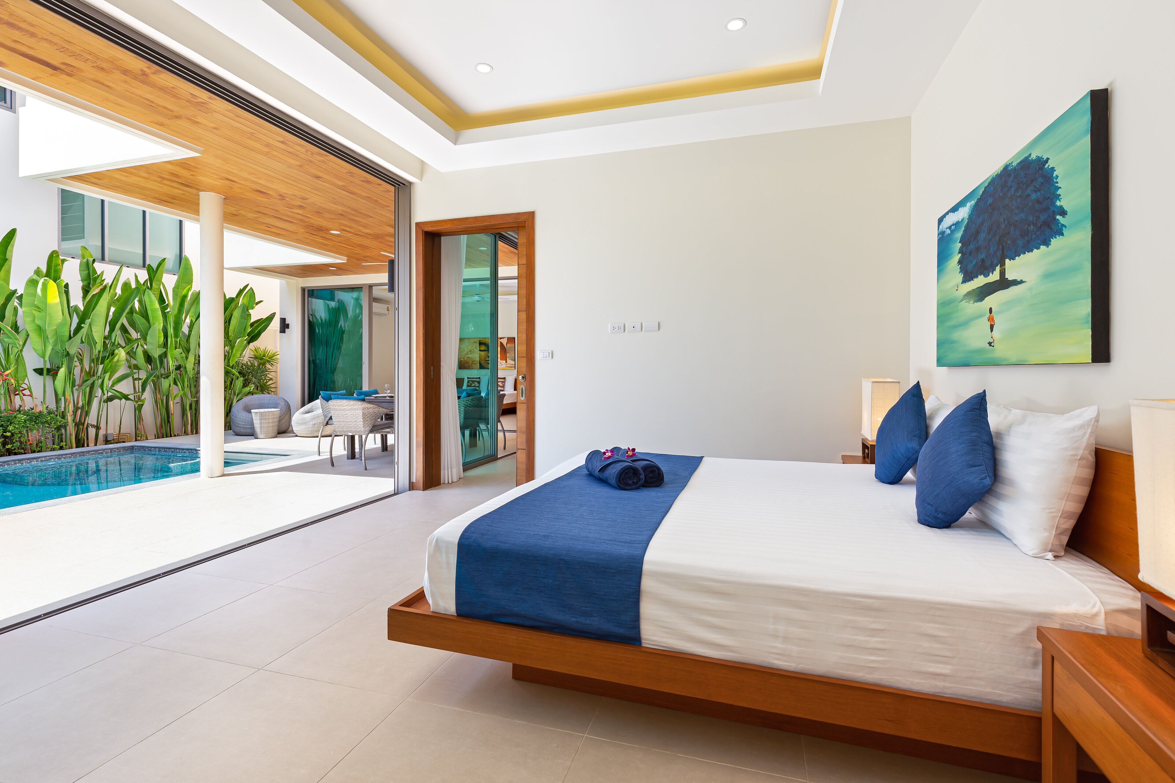 Une chambre à coucher moderne avec un grand lit, une vue sur une piscine et un tableau accroché au mur.