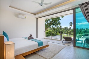 A modern bedroom with a bed, a ceiling fan, and a view of a balcony with outdoor furniture. - Trendy 4BR Villa Kari in KA Villas Rawai (Rawai)