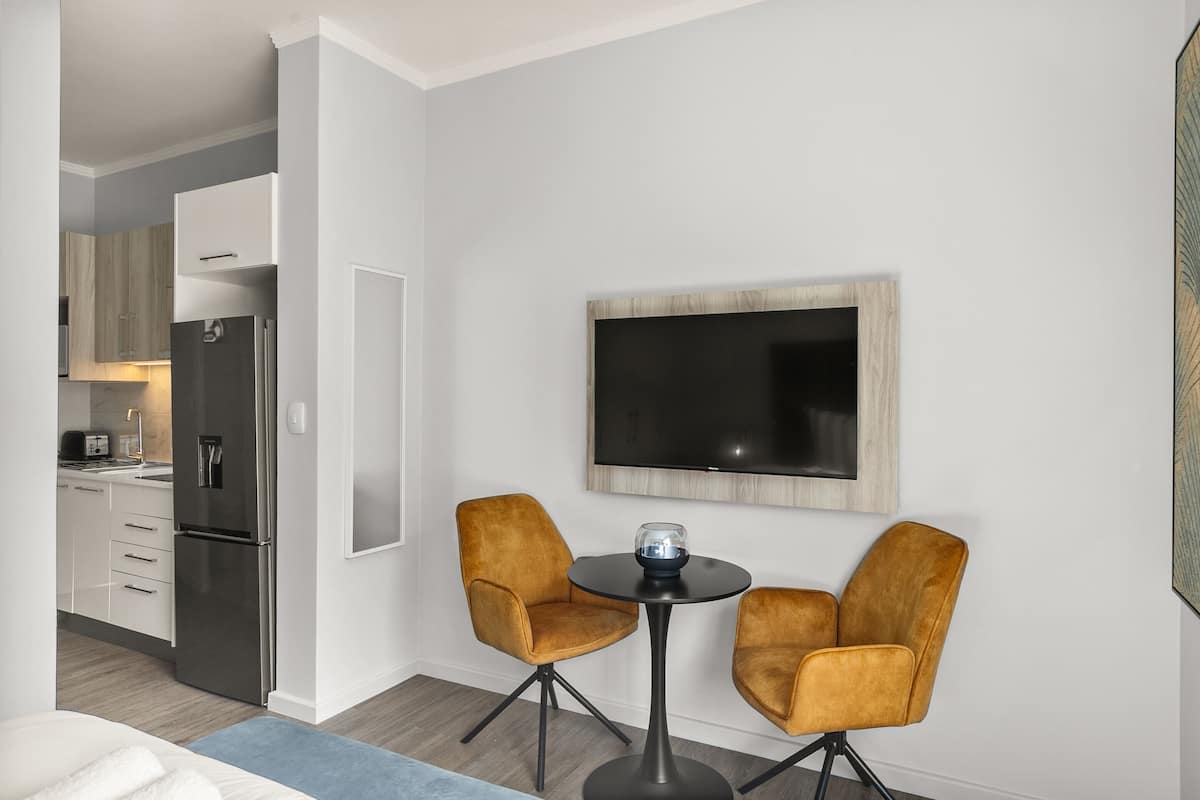 A modern kitchen with a built-in refrigerator and a dining area with two chairs and a small table.