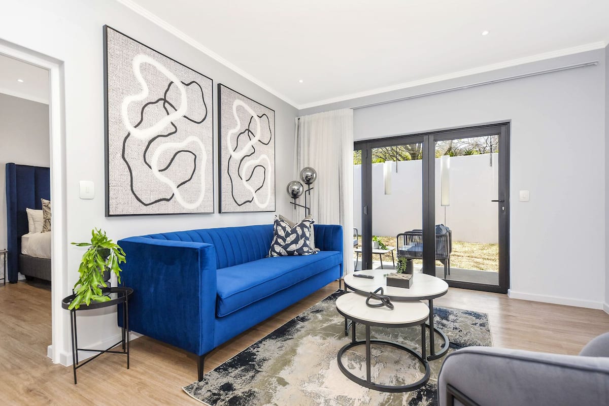 A modern living room with a blue sofa, a round coffee table, and abstract wall art.