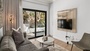 Una sala de estar moderna con un sofá gris, una mesa de centro y un televisor de pantalla plana montado en la pared.