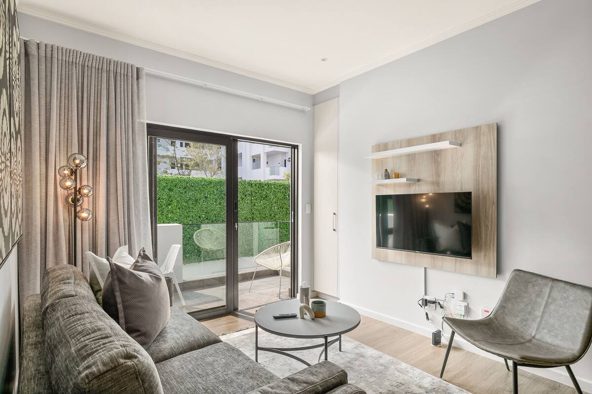 A modern living room with a sofa, a coffee table, and a TV mounted on the wall.