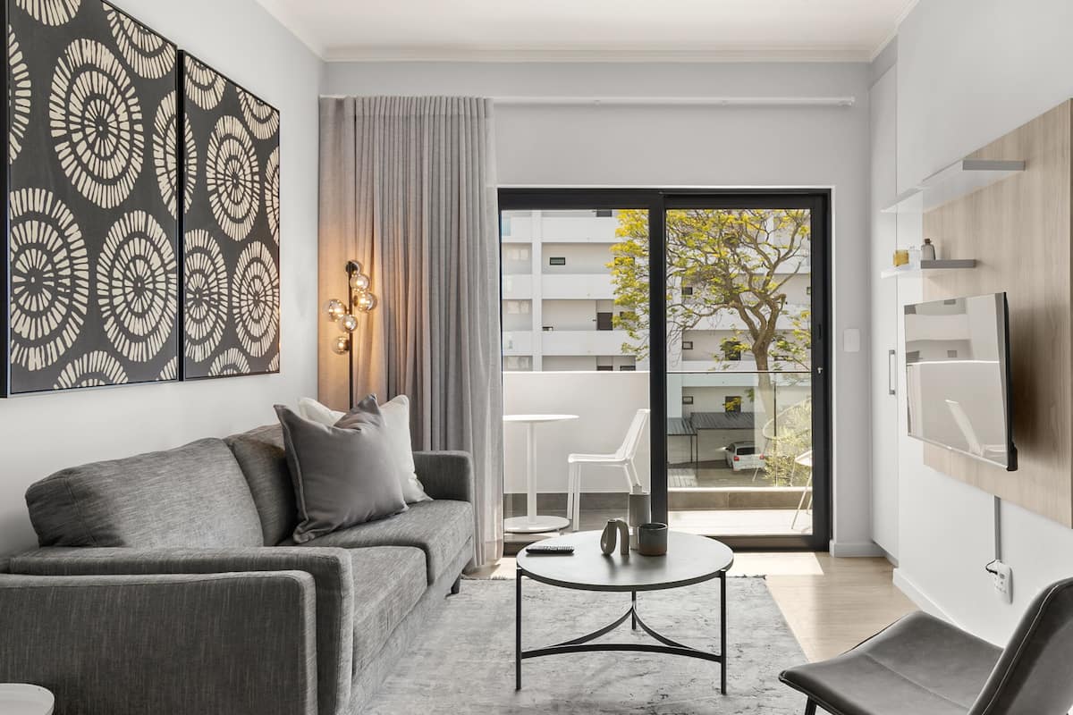 A modern living room with a grey sofa, a round coffee table, and a TV mounted on the wall.