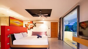 Un dormitorio moderno con una cama grande, ventilador de techo, televisor y vistas al exterior.