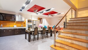 Una cocina moderna con armarios oscuros, un comedor con sillas y una escalera con escalones de madera.