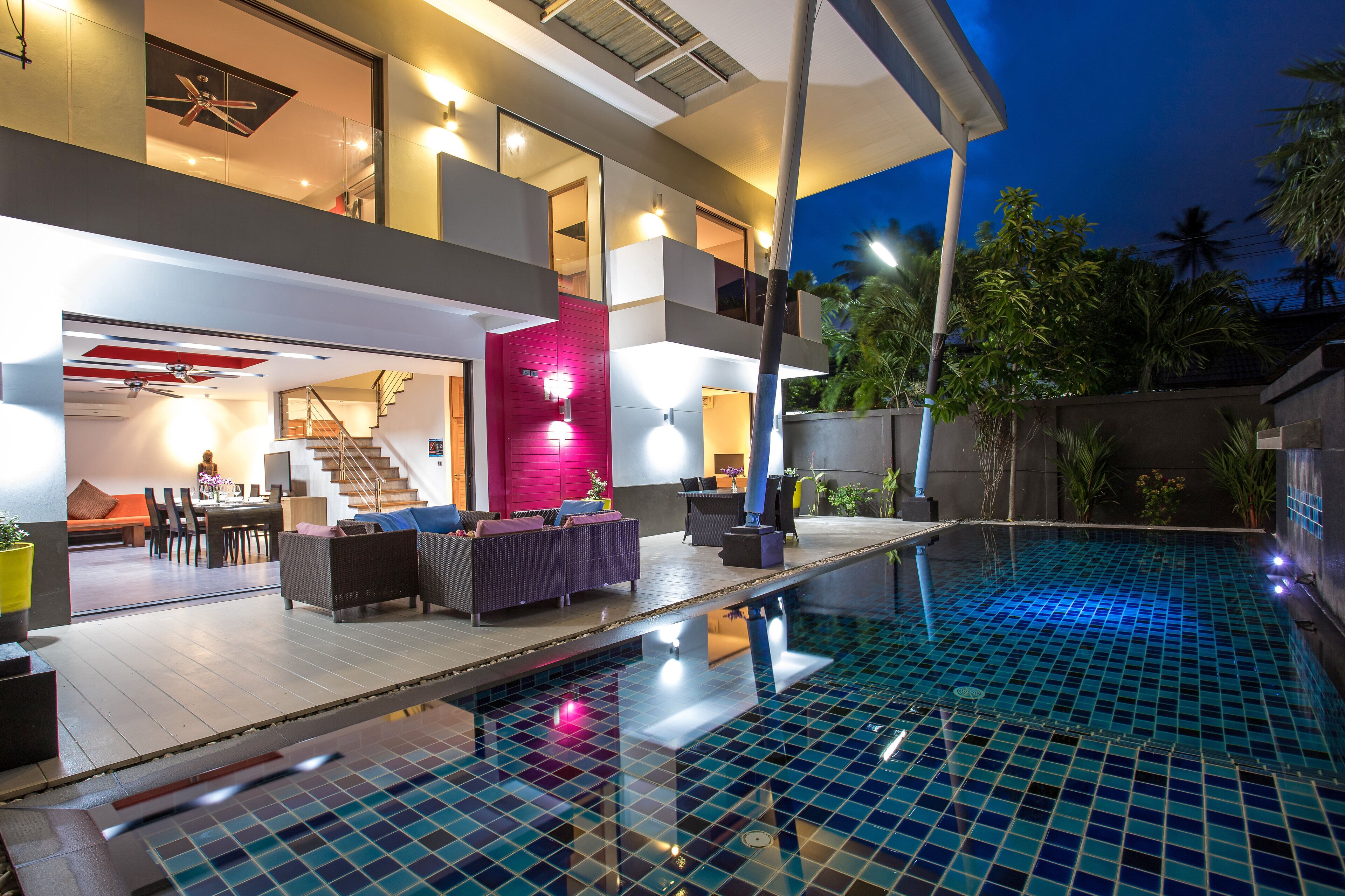 A modern house with a swimming pool, a staircase, and outdoor furniture.
