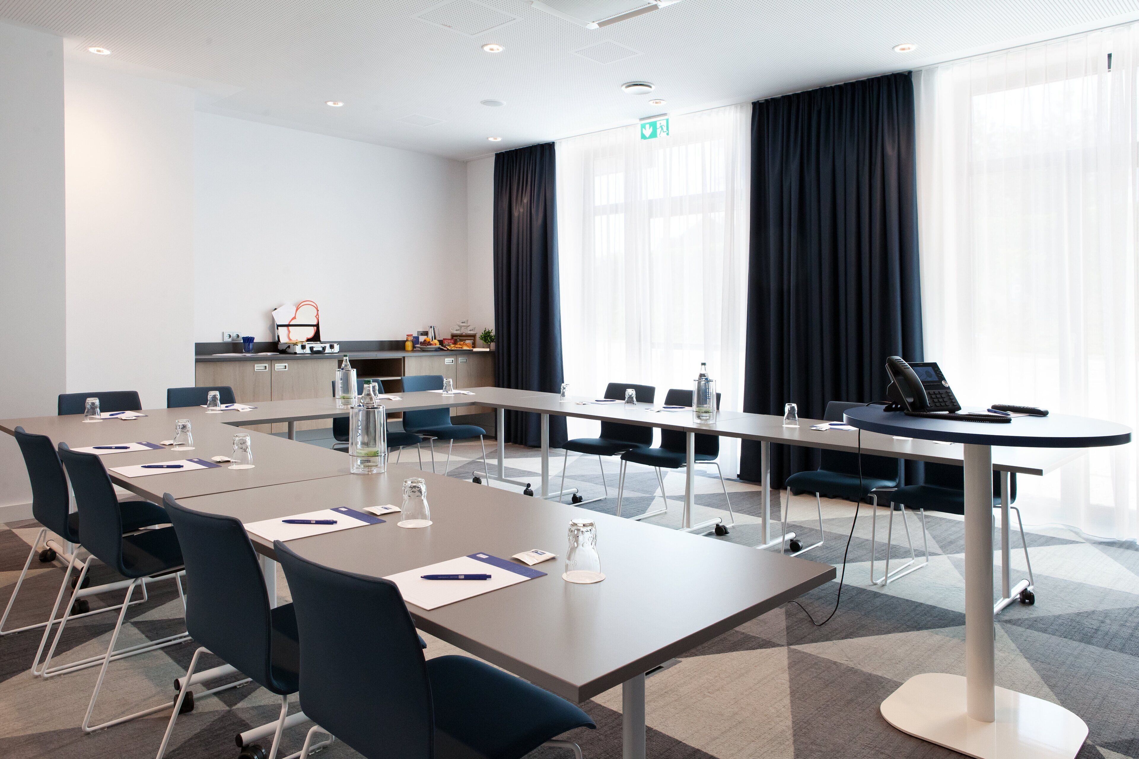 Ein Konferenzraum mit langem Tisch, Stühlen und einer kleinen Küchenzeile.