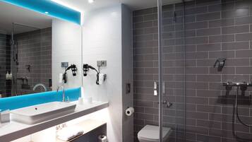 Ein modernes Badezimmer mit großem Spiegel, Waschbecken und Duschbereich.