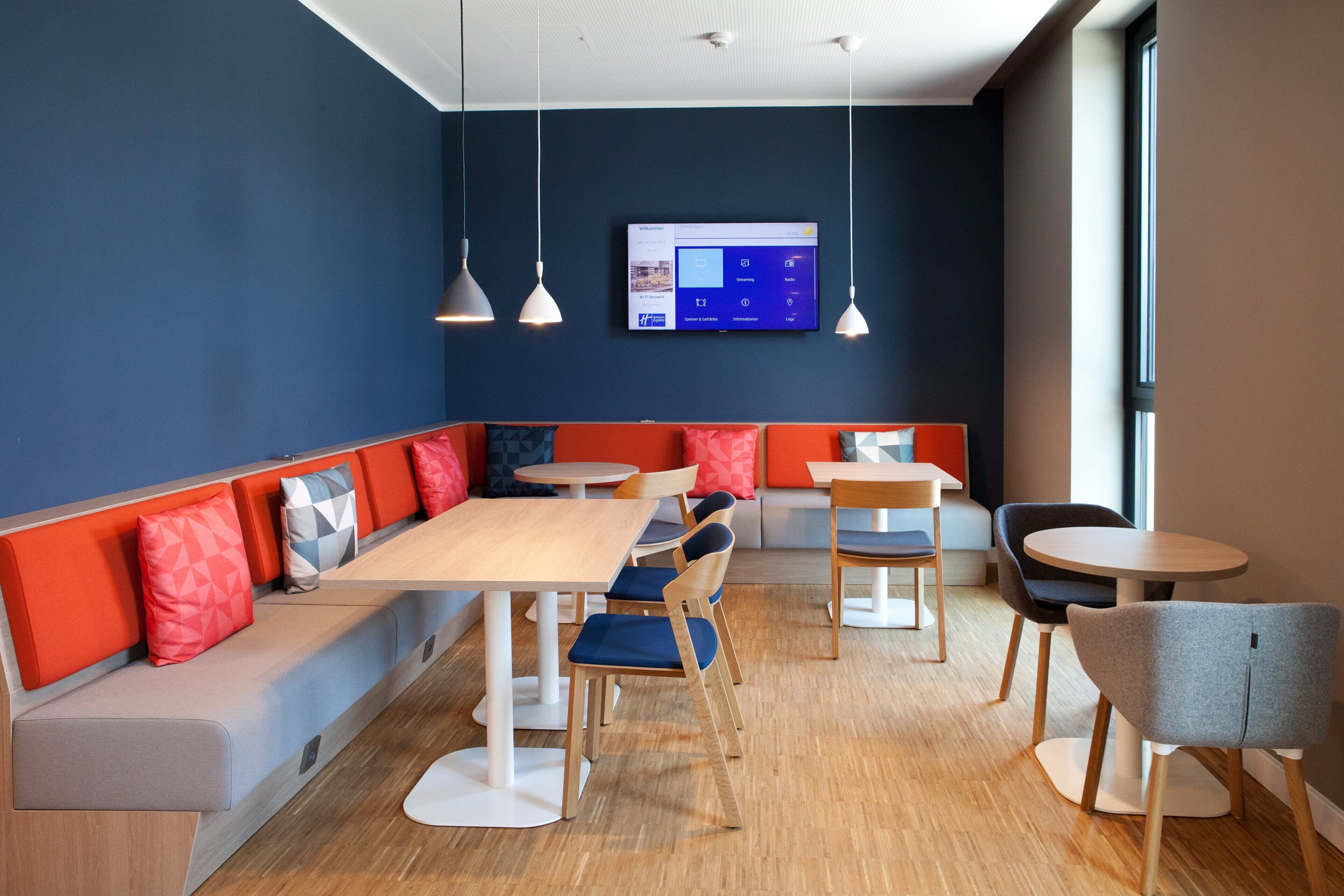 A modern dining area with a long bench, round tables, and chairs.