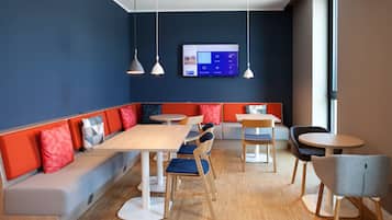 A modern dining area with a long bench, round tables, and chairs.