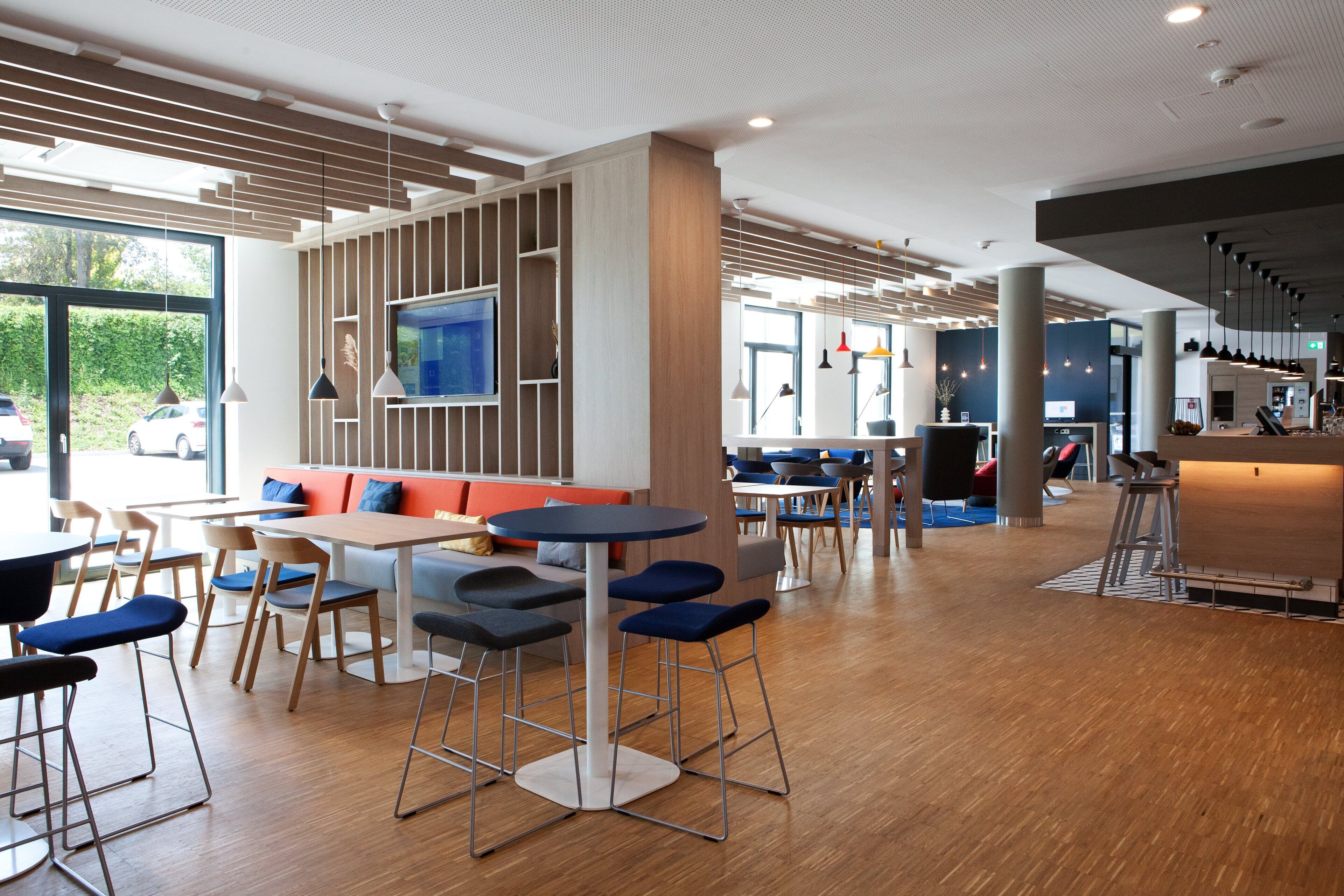Ein modernes Restaurant mit Holzboden, einer Bar und Sitzgelegenheiten mit Hocker und Tischen.