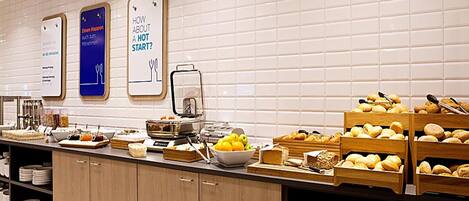 Disposição de buffet com diversos alimentos e uma máquina de café.