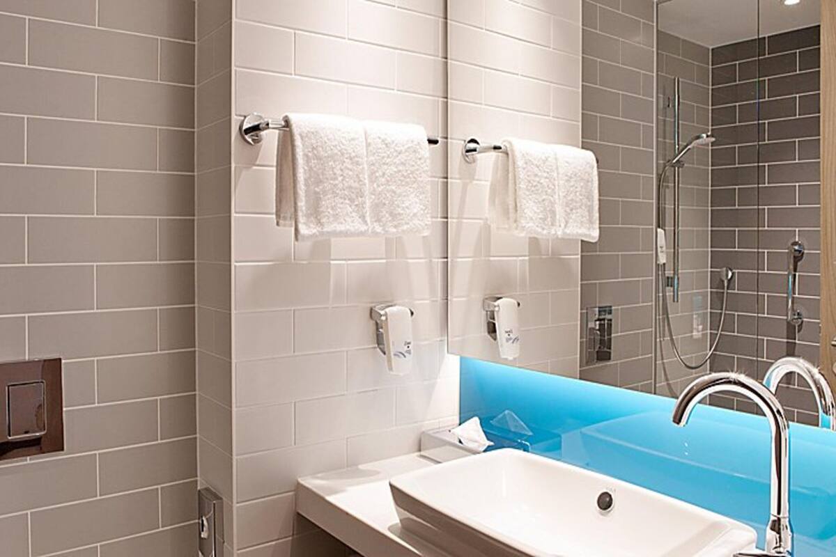 Un baño moderno con un lavamanos blanco, una pared de acento azul y una cabina de ducha de vidrio.
