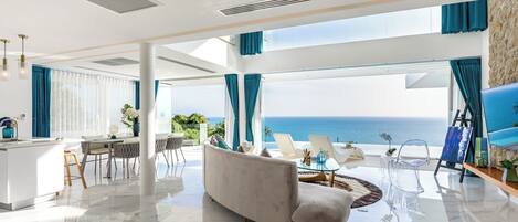 Un salón amplio con vistas al océano, un comedor y una cocina.