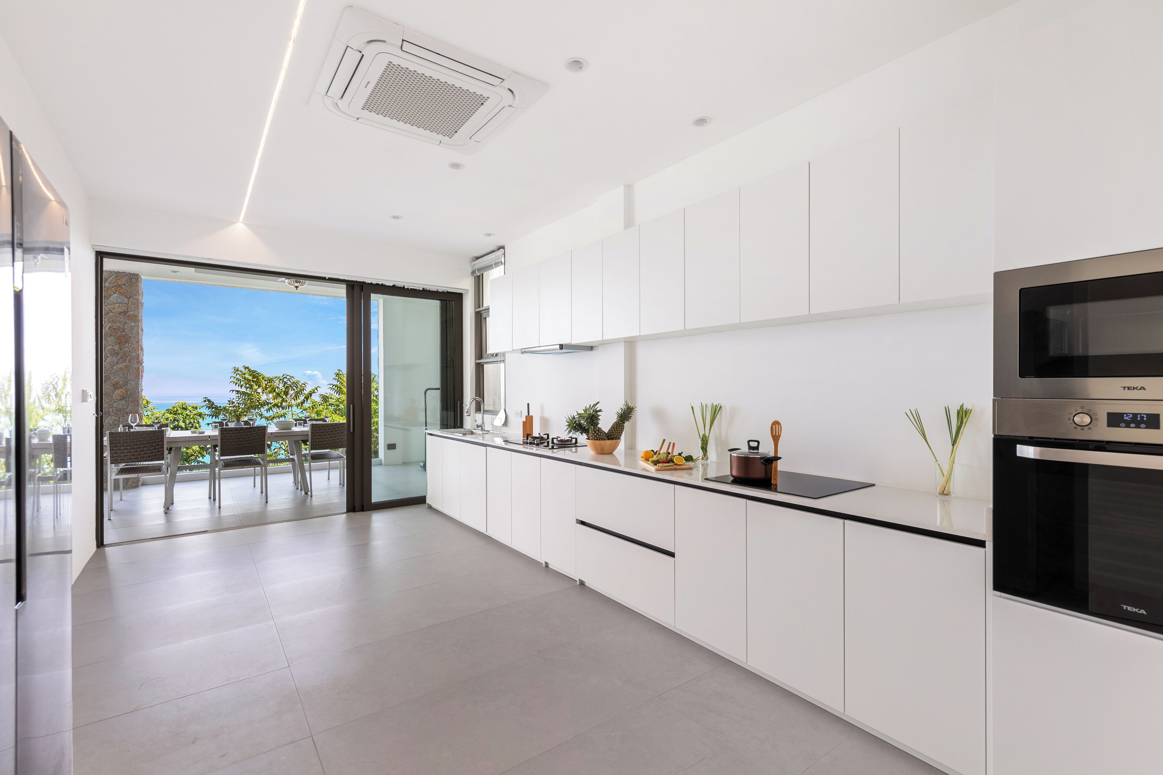A modern kitchen with white cabinets, a black countertop, and a built-in oven.