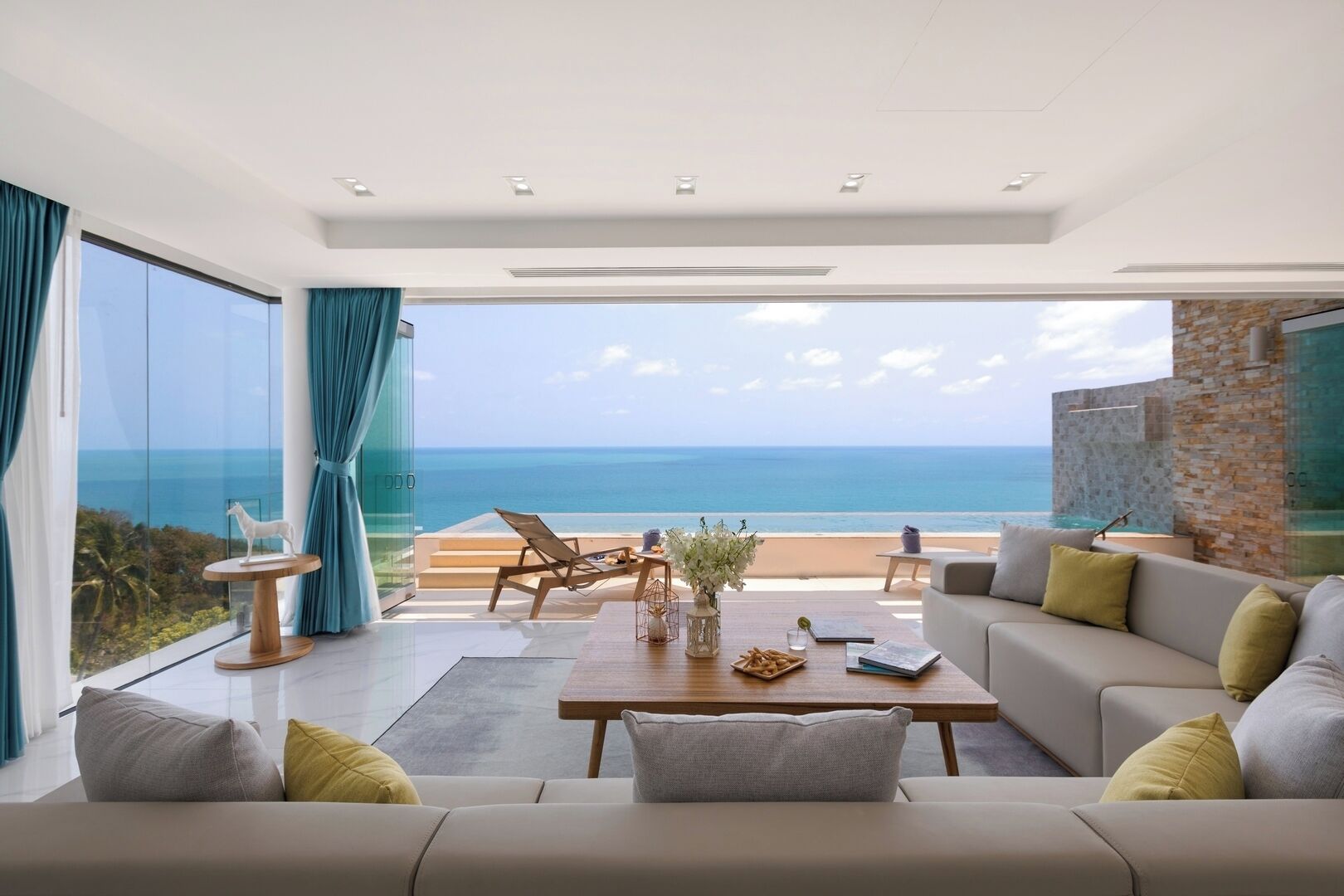 A modern living room with a large window overlooking a beach, a sofa, a coffee table, and a chair.