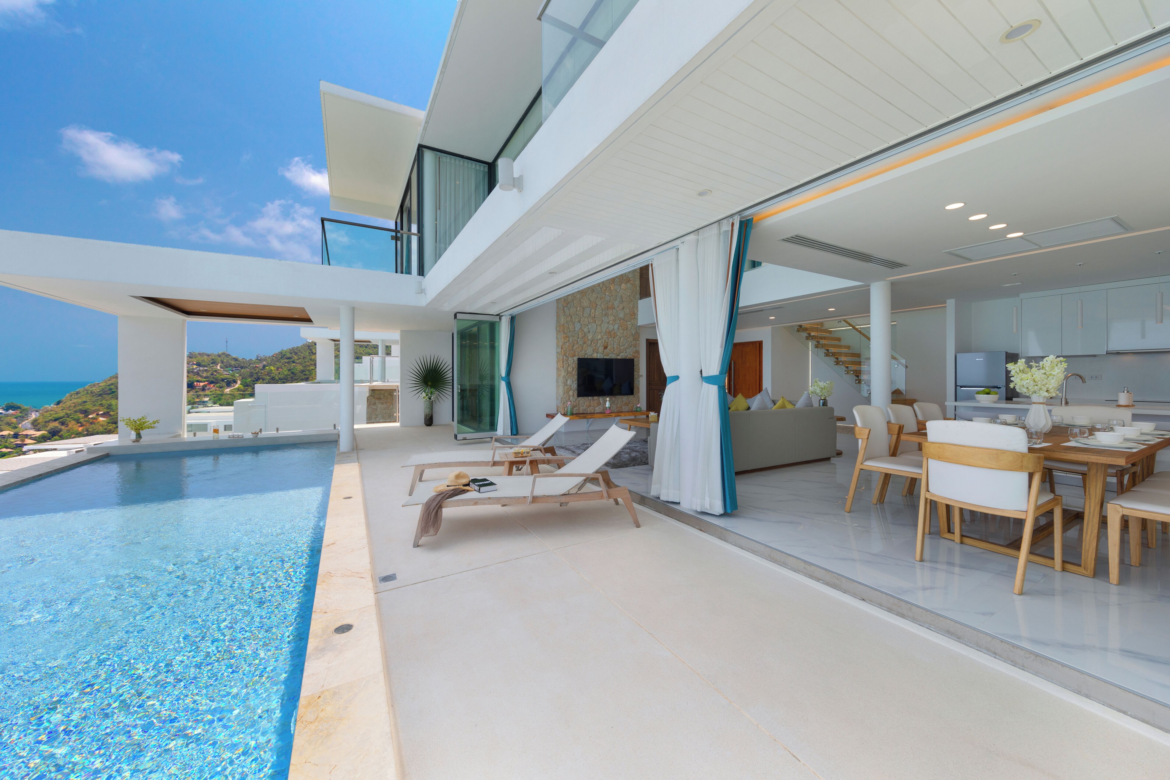 A modern house with a swimming pool, outdoor seating, and a kitchen area.