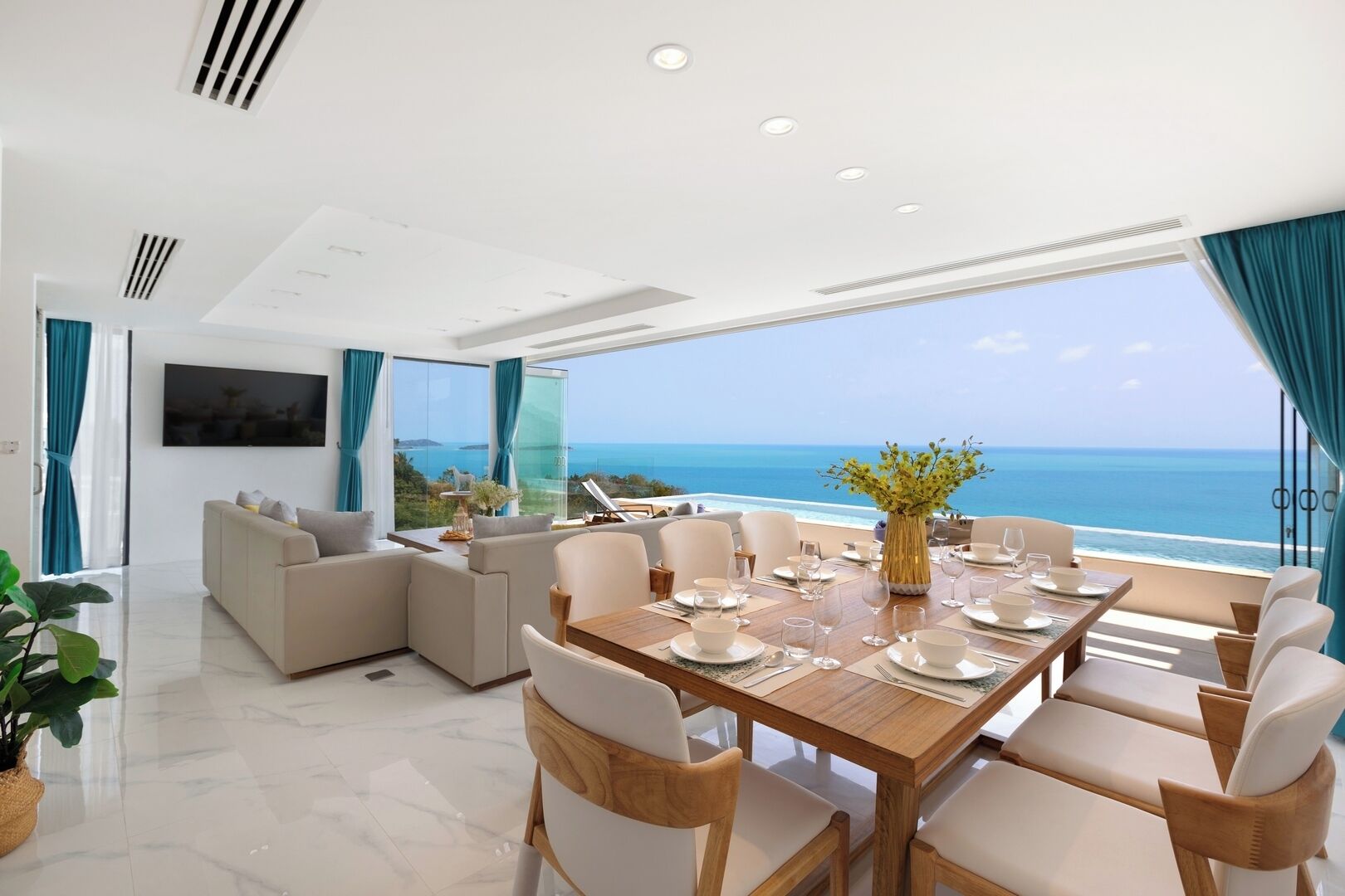 Un comedor moderno con una mesa de madera dispuesta para seis personas, con vistas a un paisaje marino.