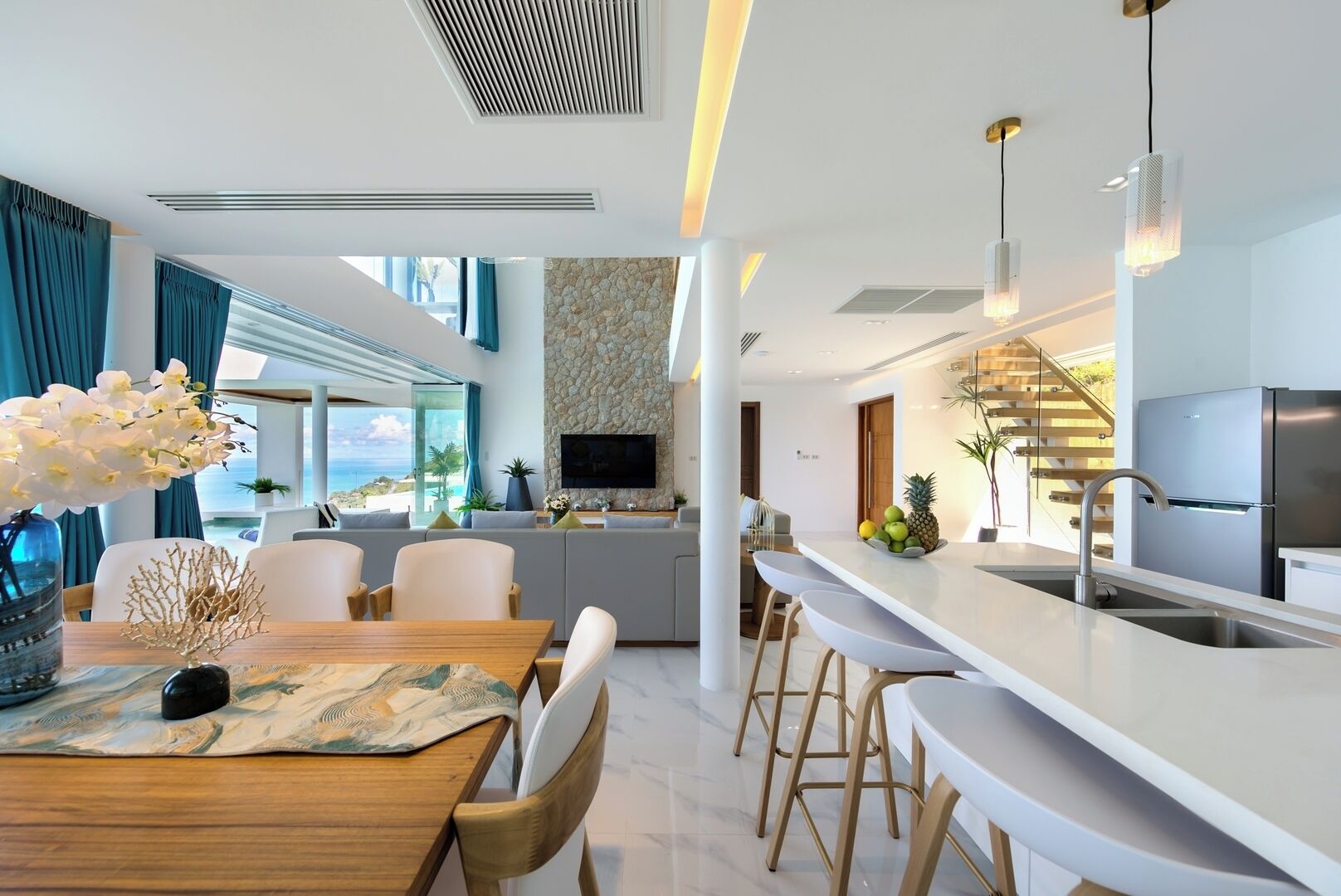 A modern kitchen with a central island, stainless steel appliances, and a view of the ocean.