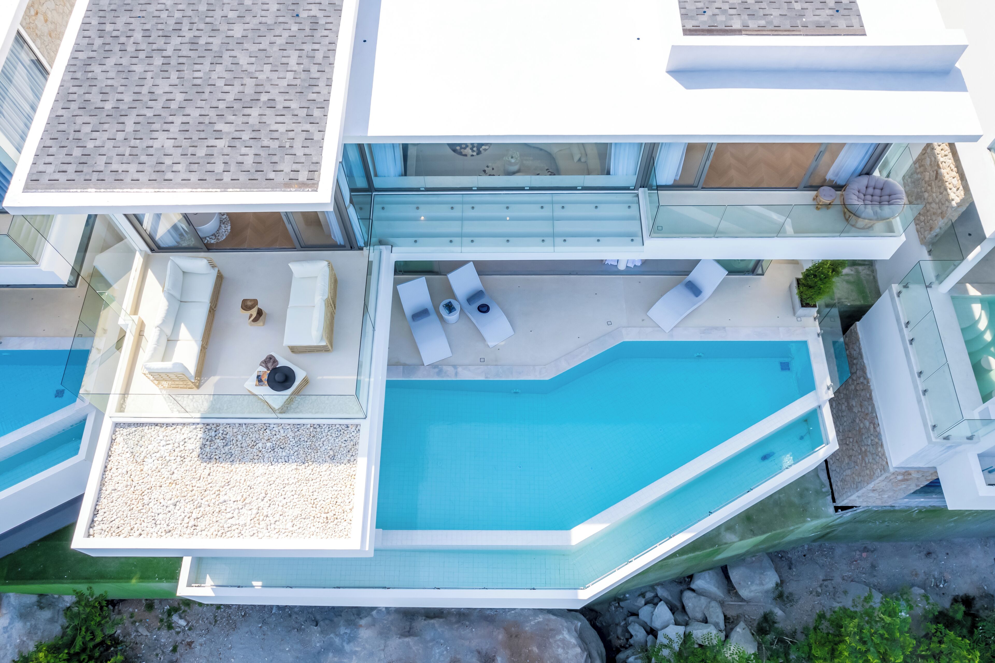 Une maison moderne à deux étages dotée d’une grande piscine, d’un espace extérieur aménagé et d’une balustrade en verre.