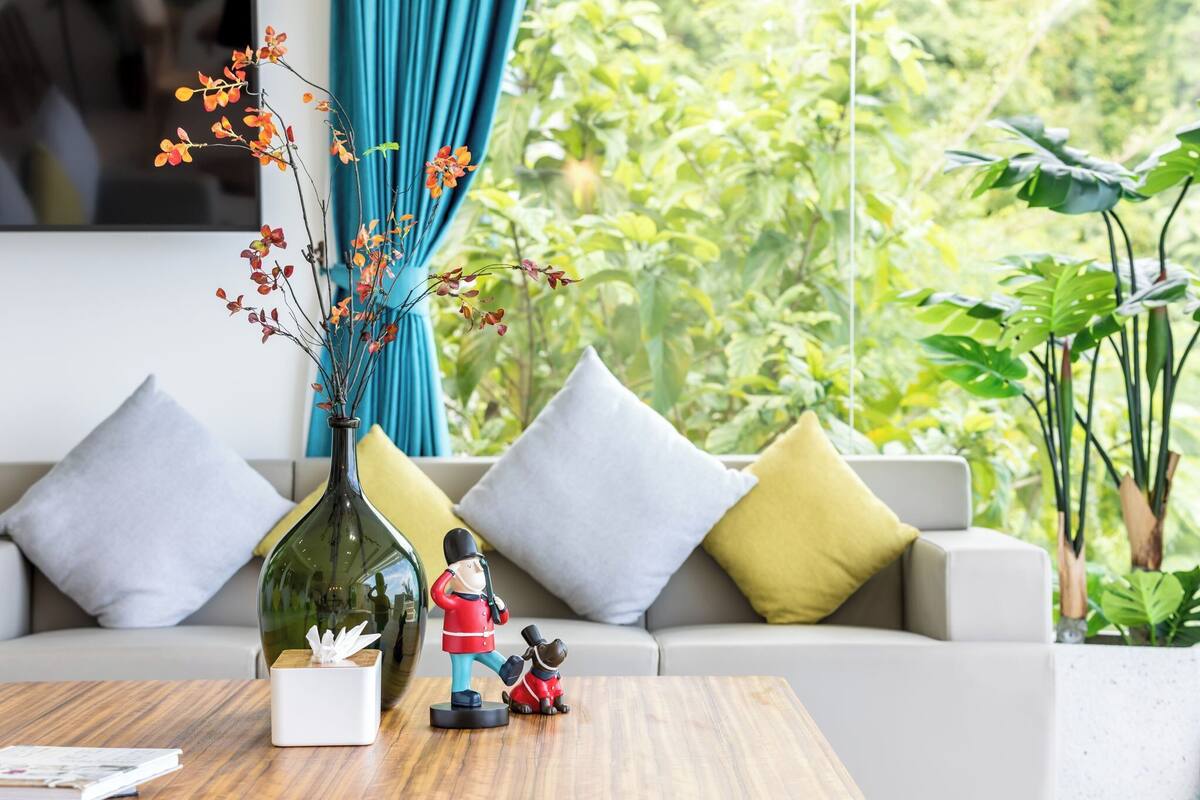 A living room with a sofa, cushions, a wooden coffee table, a decorative vase, and a figurine.