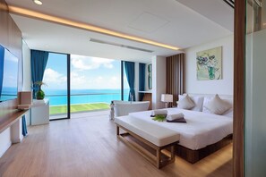 A modern hotel room with a large bed, a bench, a desk, and a view of the ocean. - Villa The Wave 2 Residence (Koh Samui)