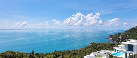 A coastal property with modern architecture, a swimming pool, and a view of the sea.