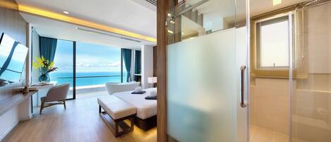 A modern hotel room with a balcony, a desk, a bed, and a shower area.