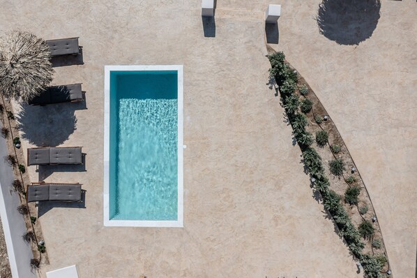 An aerial view of a swimming pool with lounge chairs and a garden area. - Golden Sand Villas (Naxos)
