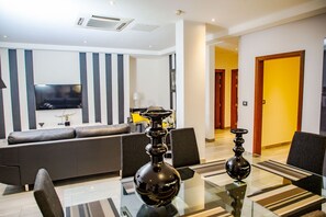 Relax in this stylish living room with a glass-top dining table and a large flat-screen TV.