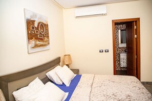 Enjoy a restful stay in this stylish room featuring a comfortable bed, a modern air conditioning unit, and a convenient bathroom with a sink.