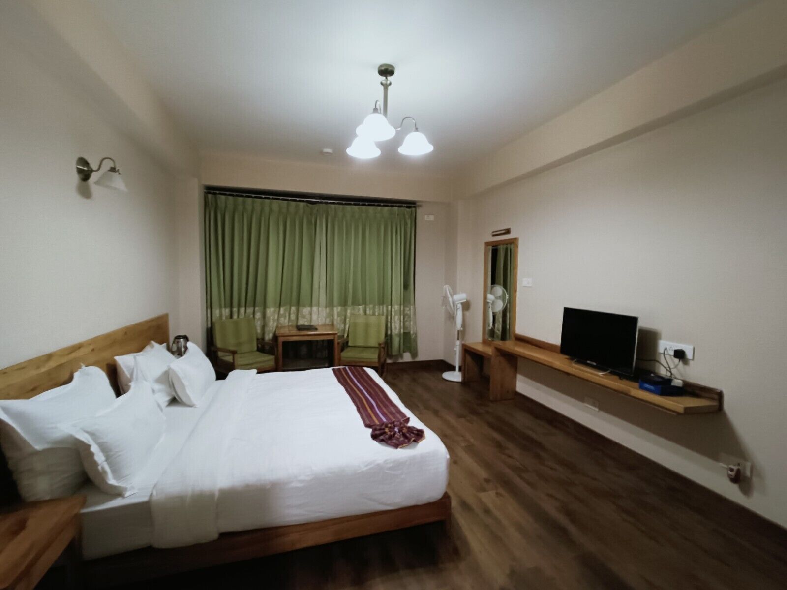 A hotel room with a bed, a desk, a TV, and a chair.