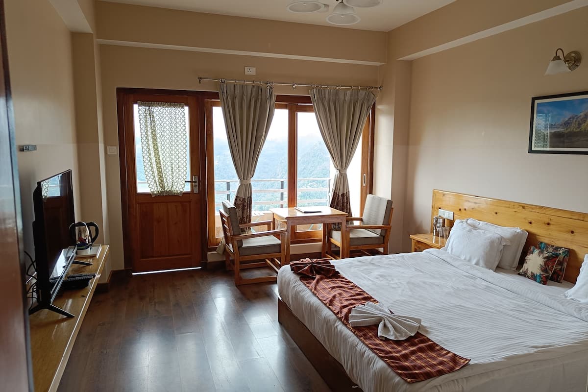 A hotel room with a bed, a desk, a chair, a television, and a view of the outdoors.